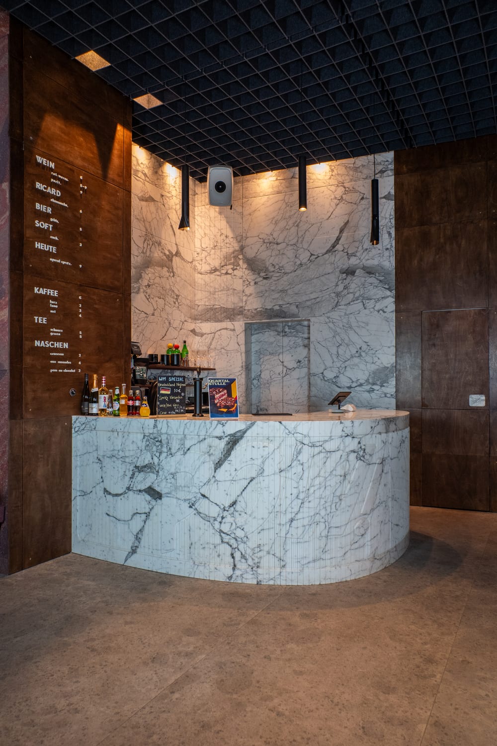 The marble counter in the café, the menu wall lit behind it.