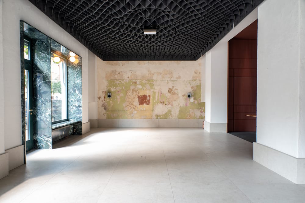 The empty hall, looking towards the window front, daylight on the screed floor.